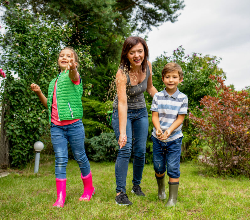 Mom with her children seeding grass in their family garden