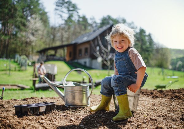 Happy small boy working outdoors in garden, sustainable lifestyle concept.